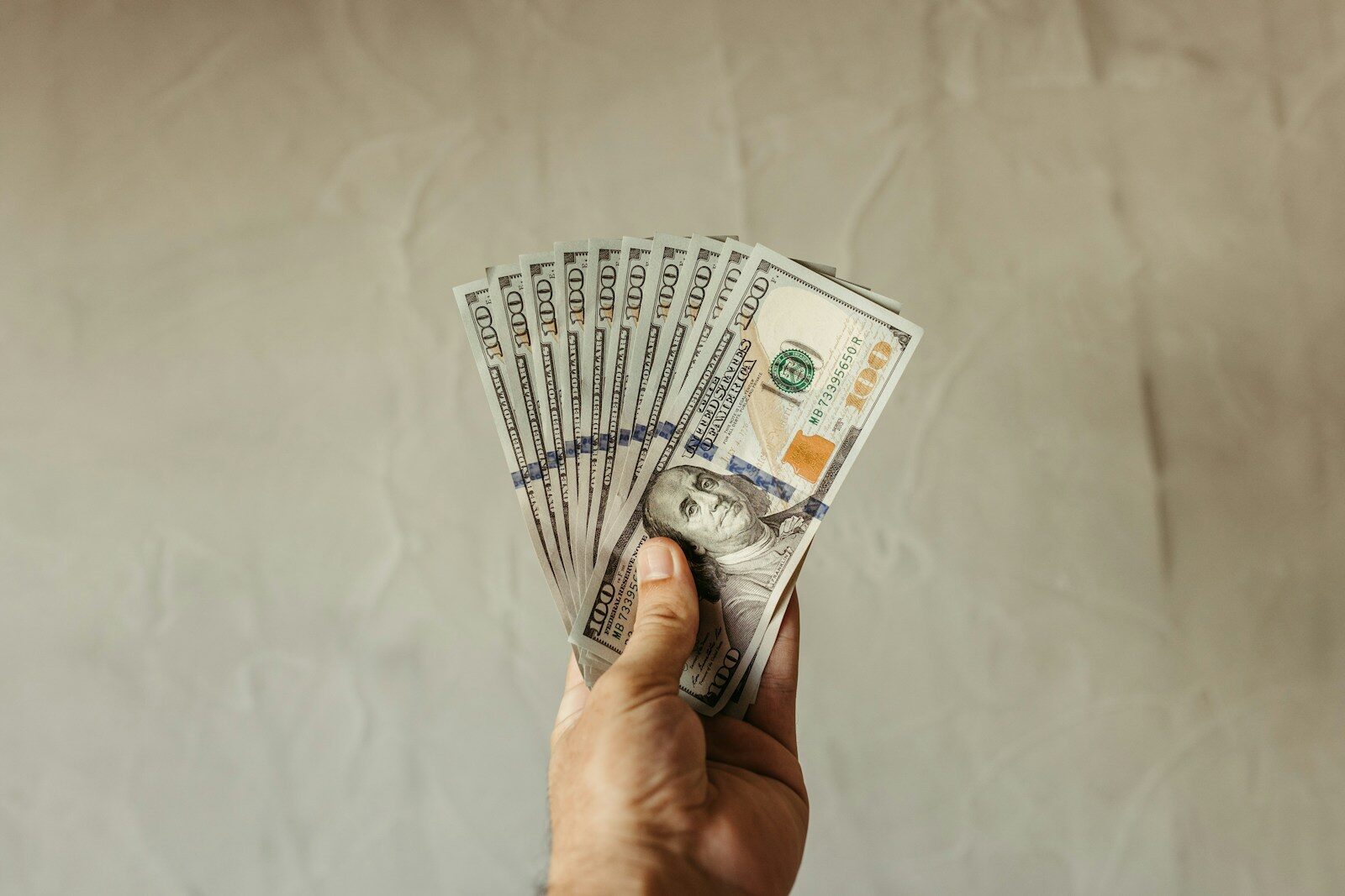 a hand holding a stack of twenty dollar bills